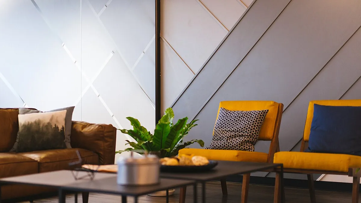 Coin salon d’un bureau, canapé, fauteuils jaunes et plante verte