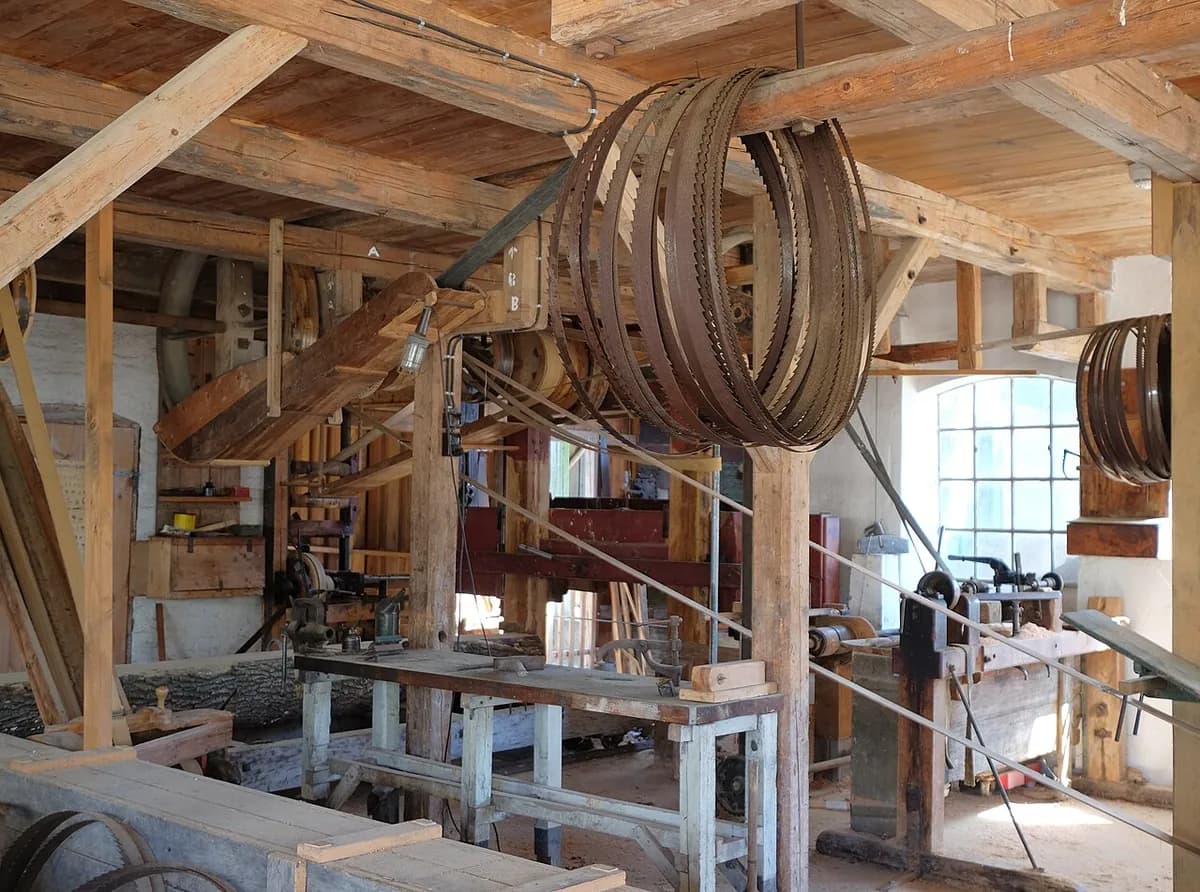Atelier de charron, établis et outils sous une charpente de bois