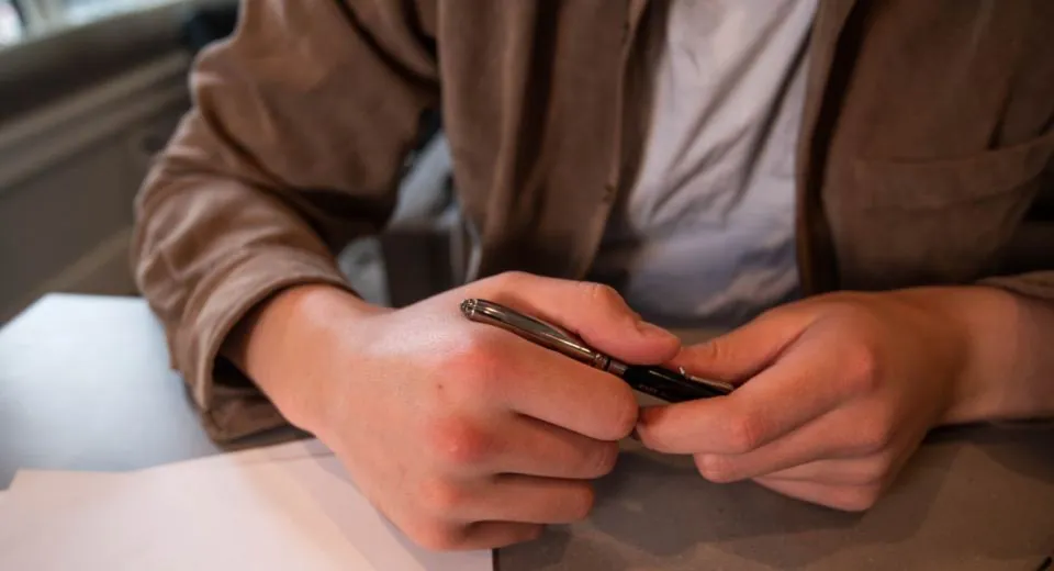 Un stylo à la main au-dessus d’un dossier ouvert, au moment de comparer deux devis d’assurance VTC